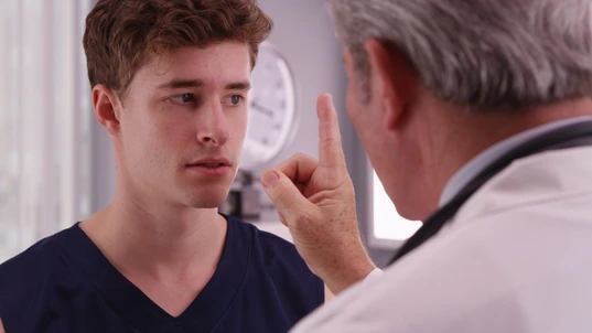 Portrait of young caucasian sports athlete having eyesight checked by doctor.