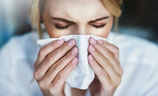 Woman with tissue and hay fever runny nose symptoms
