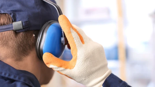 worker with hearing protectors and gloves