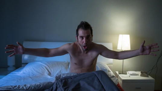 Man sleepless in his bed screaming after a terrible nightmare