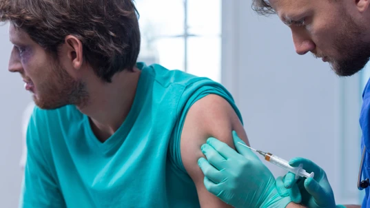 A man receiving a vaccination from a male doctor