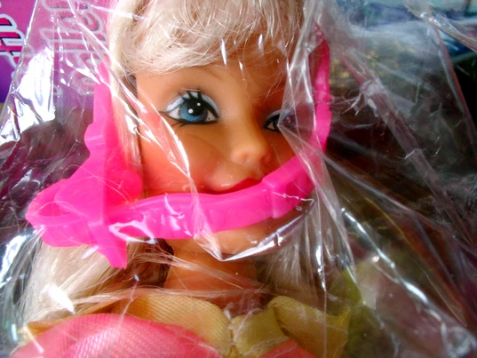 Doll with clear plastic wrapping showing childrens toys can be dangerous