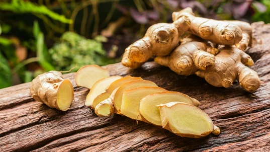 Whole and sliced pieces of ginger on a wooden table 