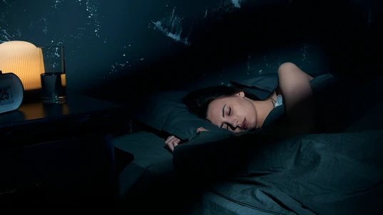 Woman sleeping soundly in a bed in a darkened room